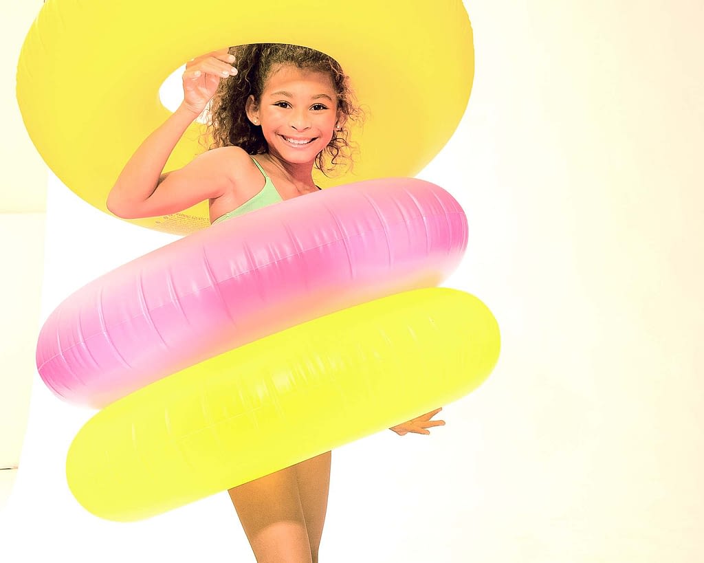 Young black girl with three float rings on a white set by commercial studio photographer Randy Schwartz