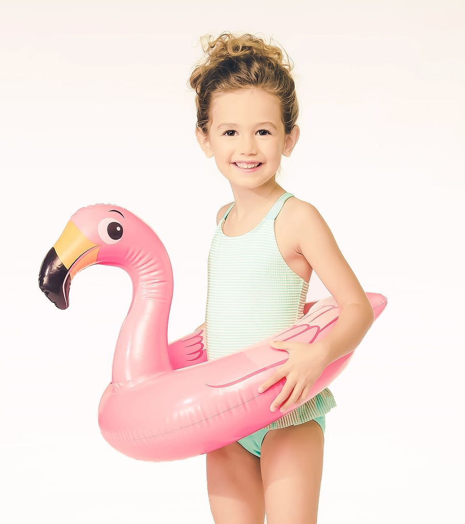 Girl on white set with flamingo float. Commercial studio photographer.